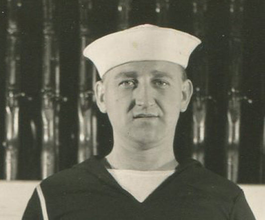 U.S. SAILOR POSED IN FRONT OF GUN RACK. B&W 5.5X3.5.