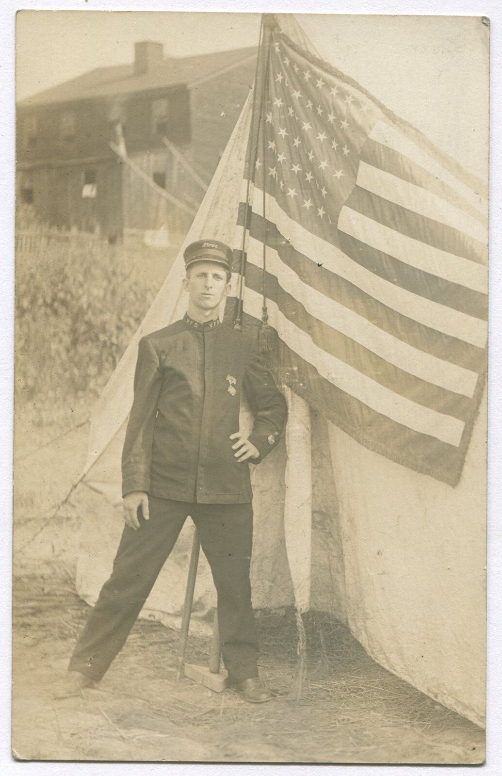Vintage Photo Postcard: Firefighter in Uniform with Flag (1900s) – Historic Fire Dept Memorabilia, Collectible