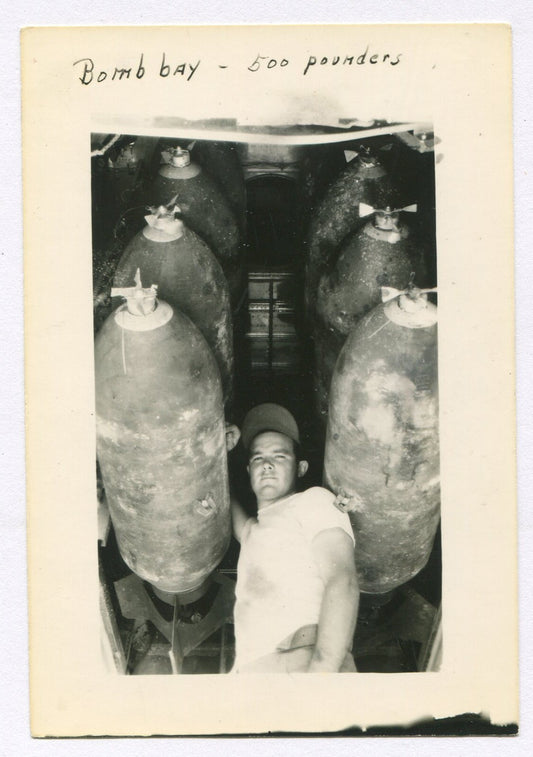 WWII SOLDIER IN BOMB BAY OF PLANE/500 LB BOMBS. 5X3.5 B&W.