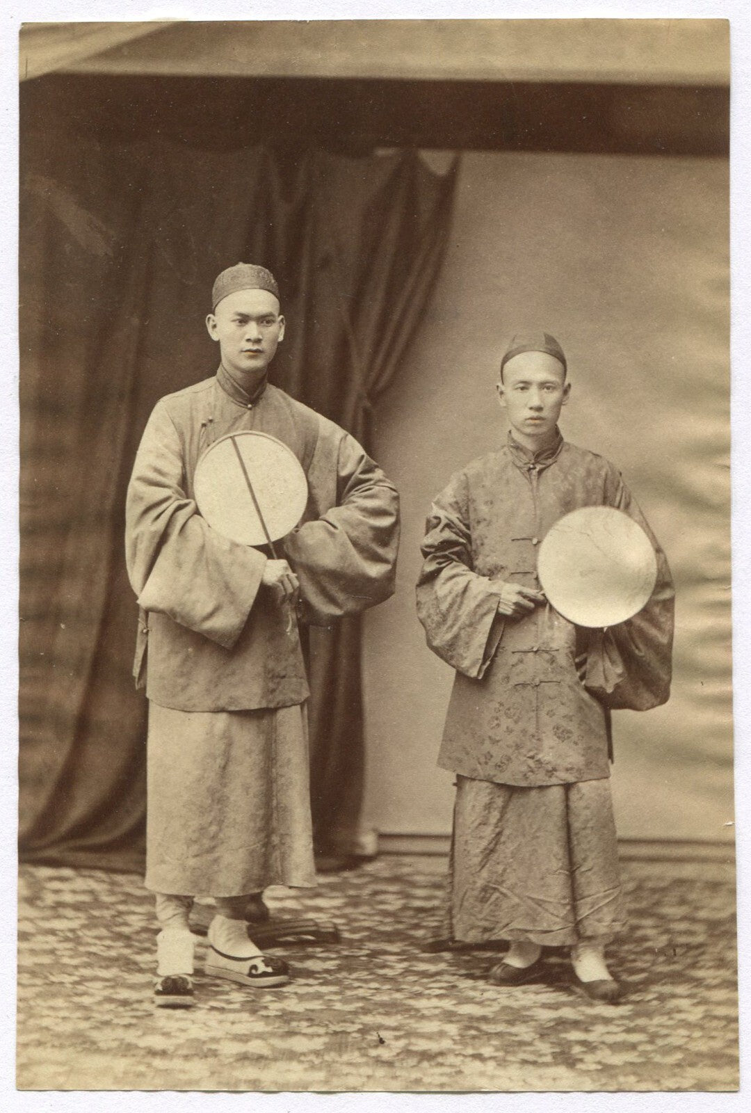 TWO CHINESE MEN, TRADITIONAL ATTIRE, HOLDING DRUMS. 1880s. TINTED ALBUMEN.