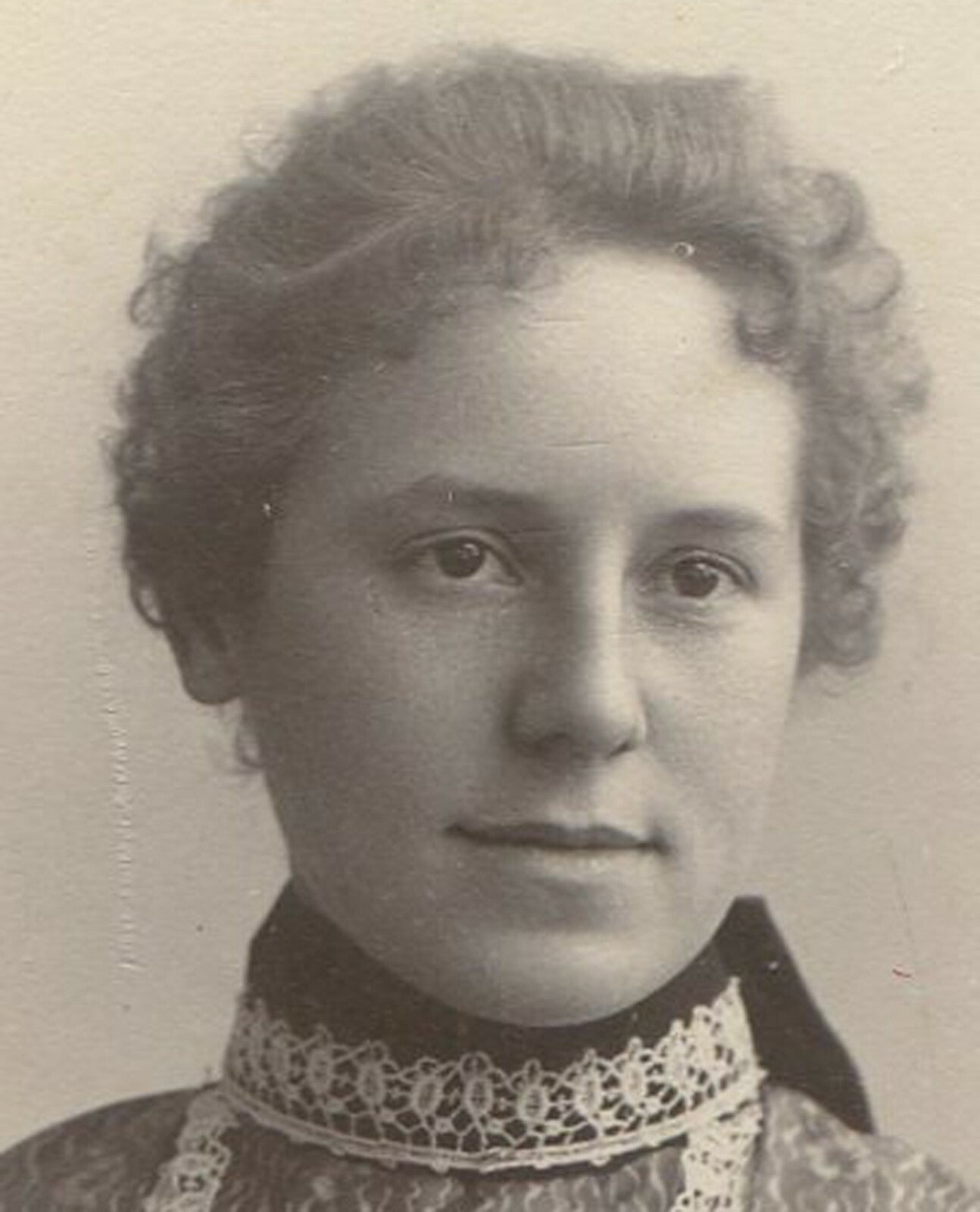 WOMAN, CURLY HAIR AND ORNATE DRESS. SCALLOPED EDGED CARD. 1900s. 4X3 INCHES.
