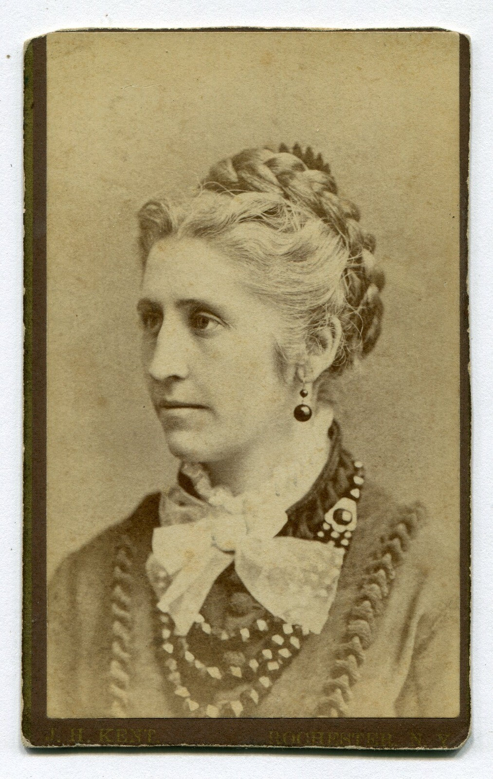 WOMAN W/FRENCH BRAID, BIG BEADED NECKLACE AND LACE BOW TIE. CDV. ROCHESTER,N.Y.