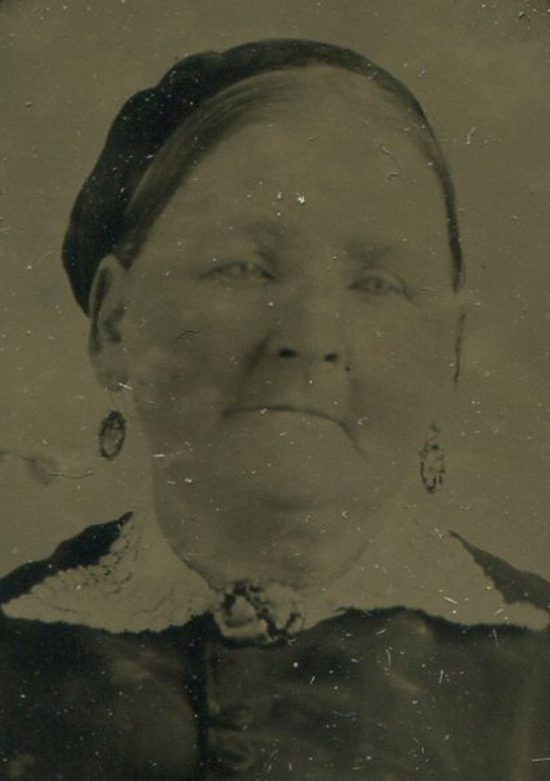 OLDER WOMAN, EARRINGS, KNOWING EXPRESSION. TINTYPE IN PERIOD PAPER MAT.