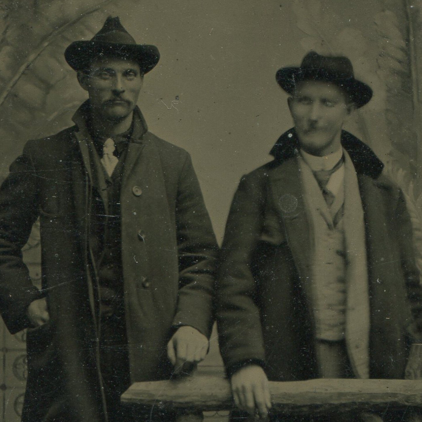 TWO MEN IN SUITS W/HATS, OVERCOATS. TINTYPE, PAINTED BACKGROUND.