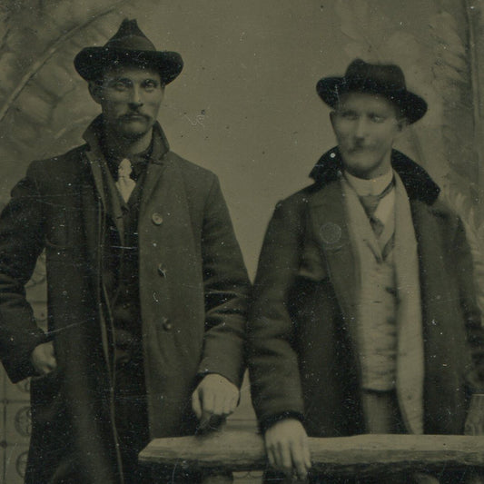 TWO MEN IN SUITS W/HATS, OVERCOATS. TINTYPE, PAINTED BACKGROUND.