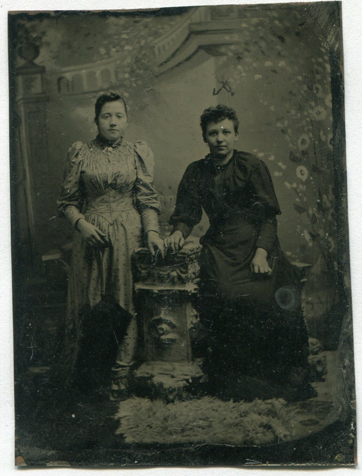 TWO WOMEN, STANDING POSE. ORNATE PAINTED BACKGROUND. TINTYPE.