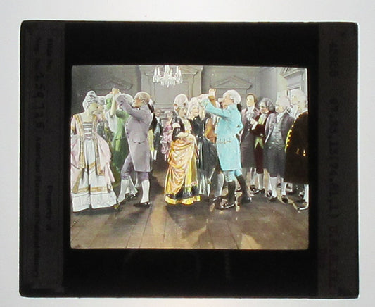 ACTORS PORTRAY COLONIAL SOCIAL GATHERING. HAND COLORED PHOTO ON GLASS.