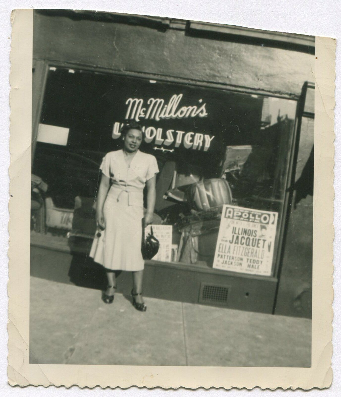 AFRICAN AMERICAN WOMAN POSED IN FRONT OF UPHOLSTERY SHOP. B&W SNAPSHOT.