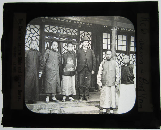 YOUNG MEN IN TRADITIONAL CHINESE CLOTHING POSED W/ WESTERN MAN. LANTERN SLIDE.