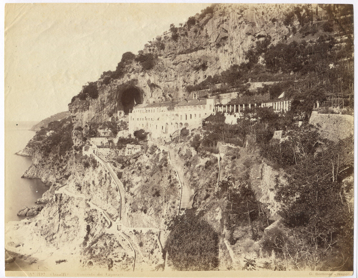 VILLAGE CLINGS TO CLIFFS ABOVE SEA. STAIRS CLIMB THE HILLSIDES TO A VILLAGE.