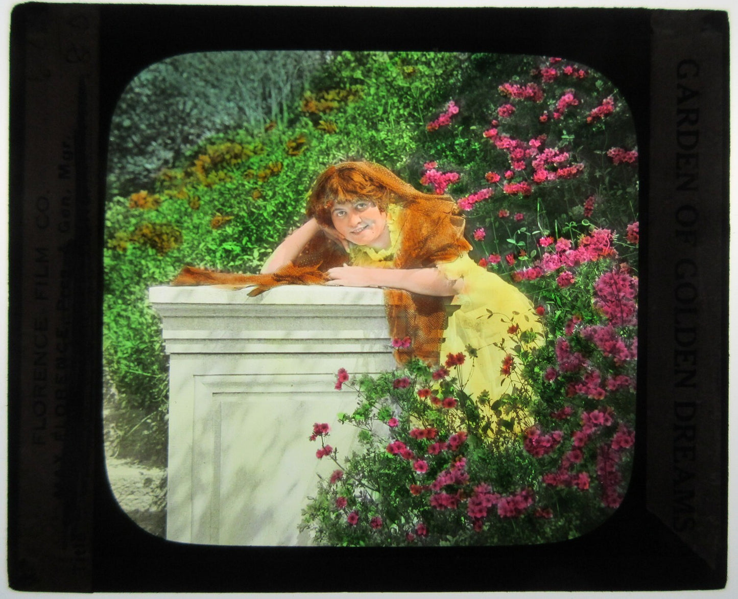 RED HAIRED WOMAN POSED IN GARDEN. HAND COLORED PHOTO ON GLASS.