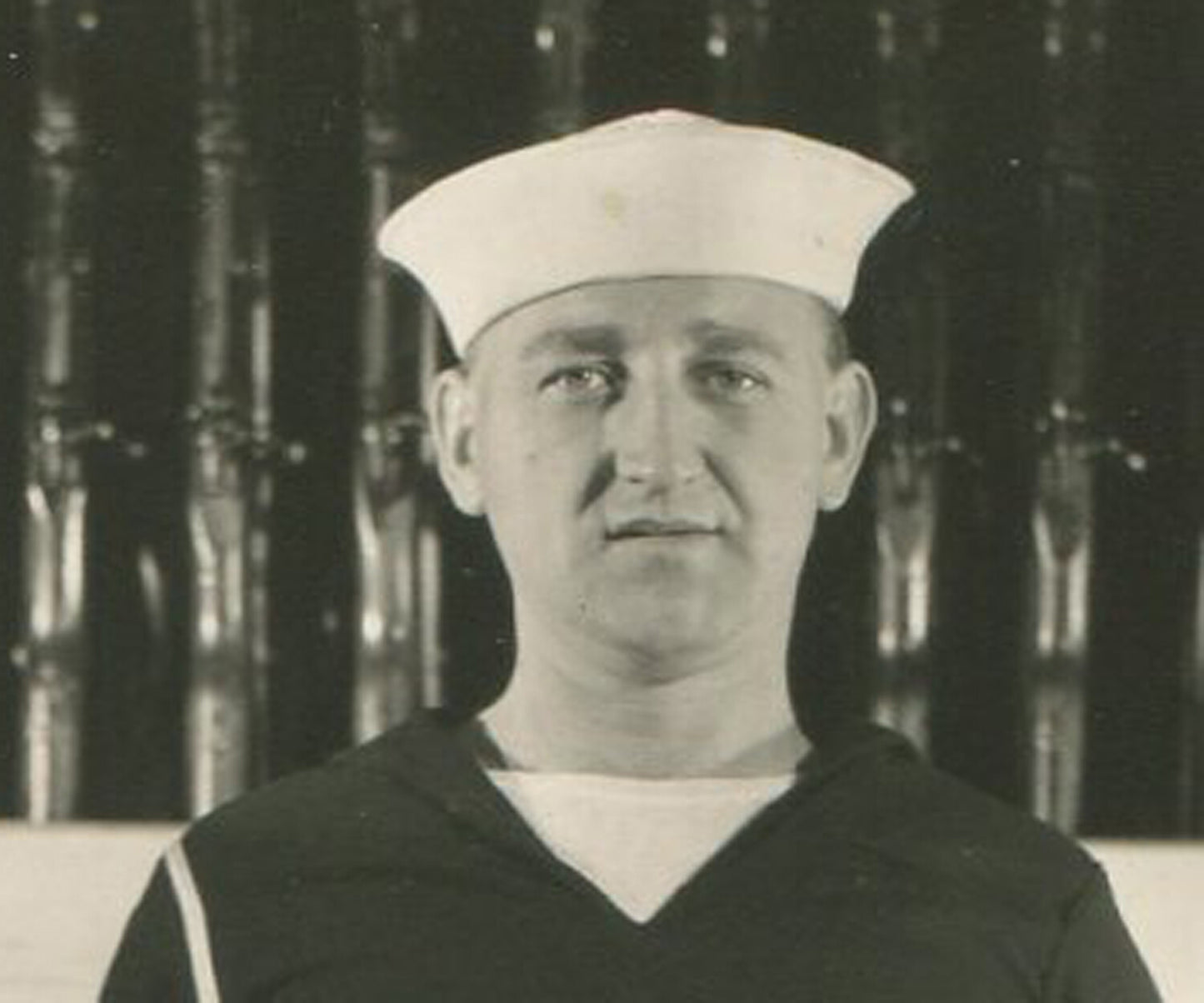 Vintage black-and-white photograph of U.S. sailor in front of gun rack, 5.5x3.5 in, original photo wall decor