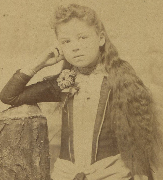 YOUNG GIRL W/VERY LONG HAIR, POSED LEANING ON TABLE. CABINET CARD.TRIMMED SIDES.