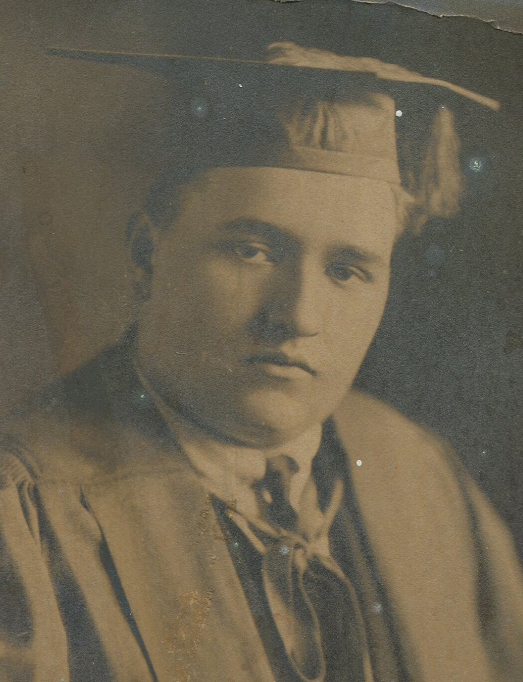 SAD, GLUM GRADUATE IN CAP AND GOWN, THINKING OF HIS STUDENT DEBT. CIRCA 1930.