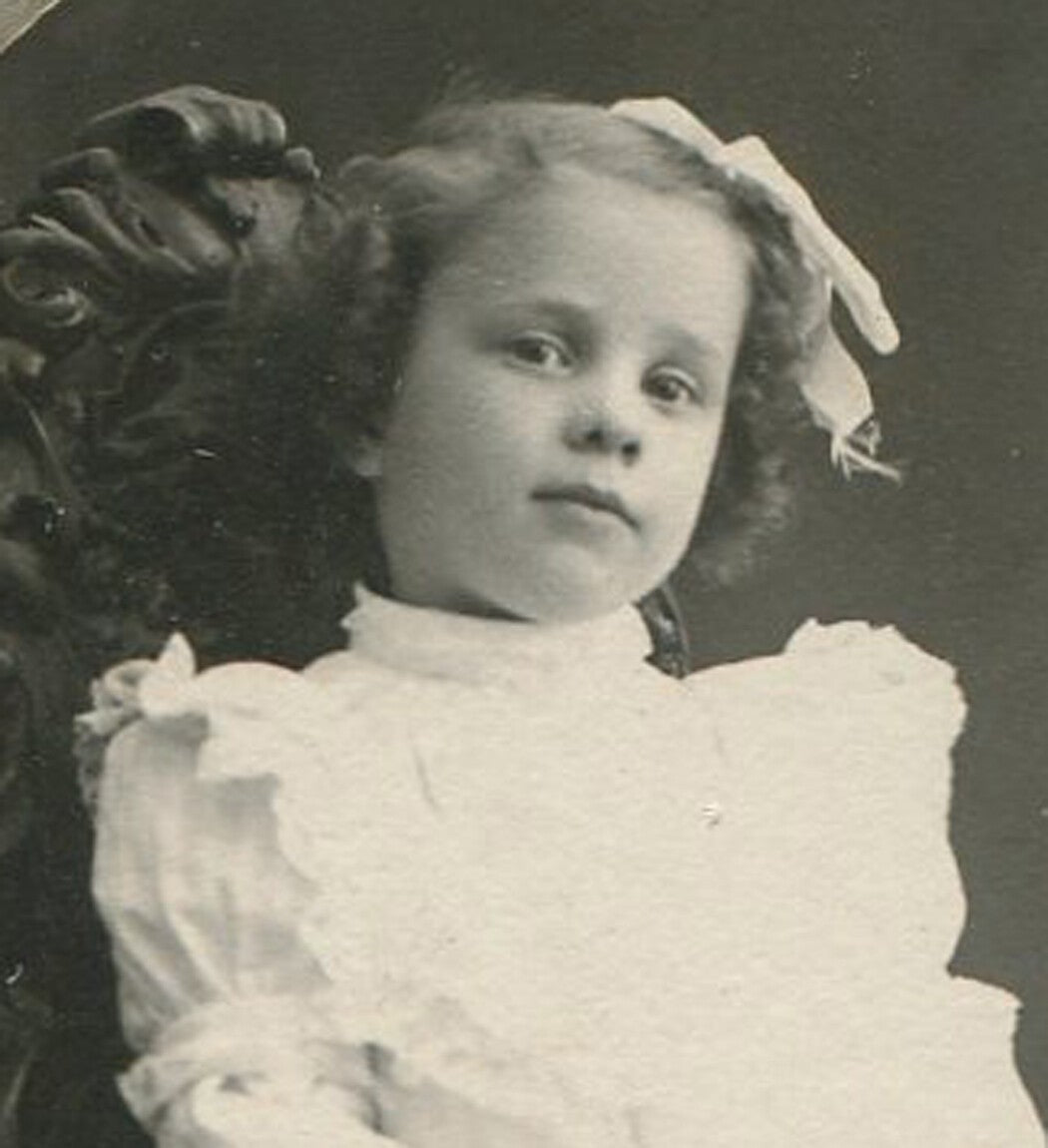 Vintage photograph: little girl with large hair bow, menacing pose, oval silver