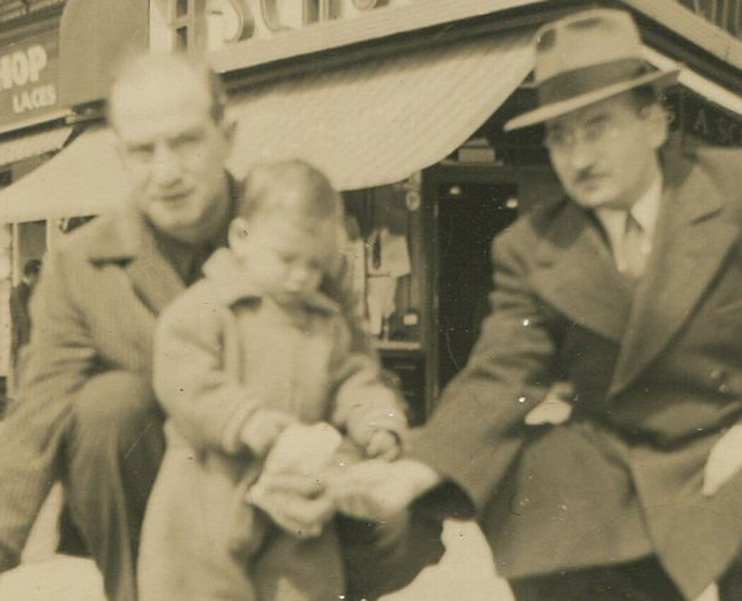 Vintage 1940s black-and-white photo: man helping toddler feed a pigeon - retro
