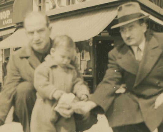 Vintage 1940s black-and-white photo: man helping toddler feed a pigeon - retro