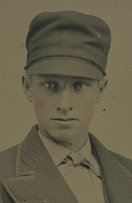 Vintage tintype portrait: young man in railroad hat, wide-lapel suit, tinted
