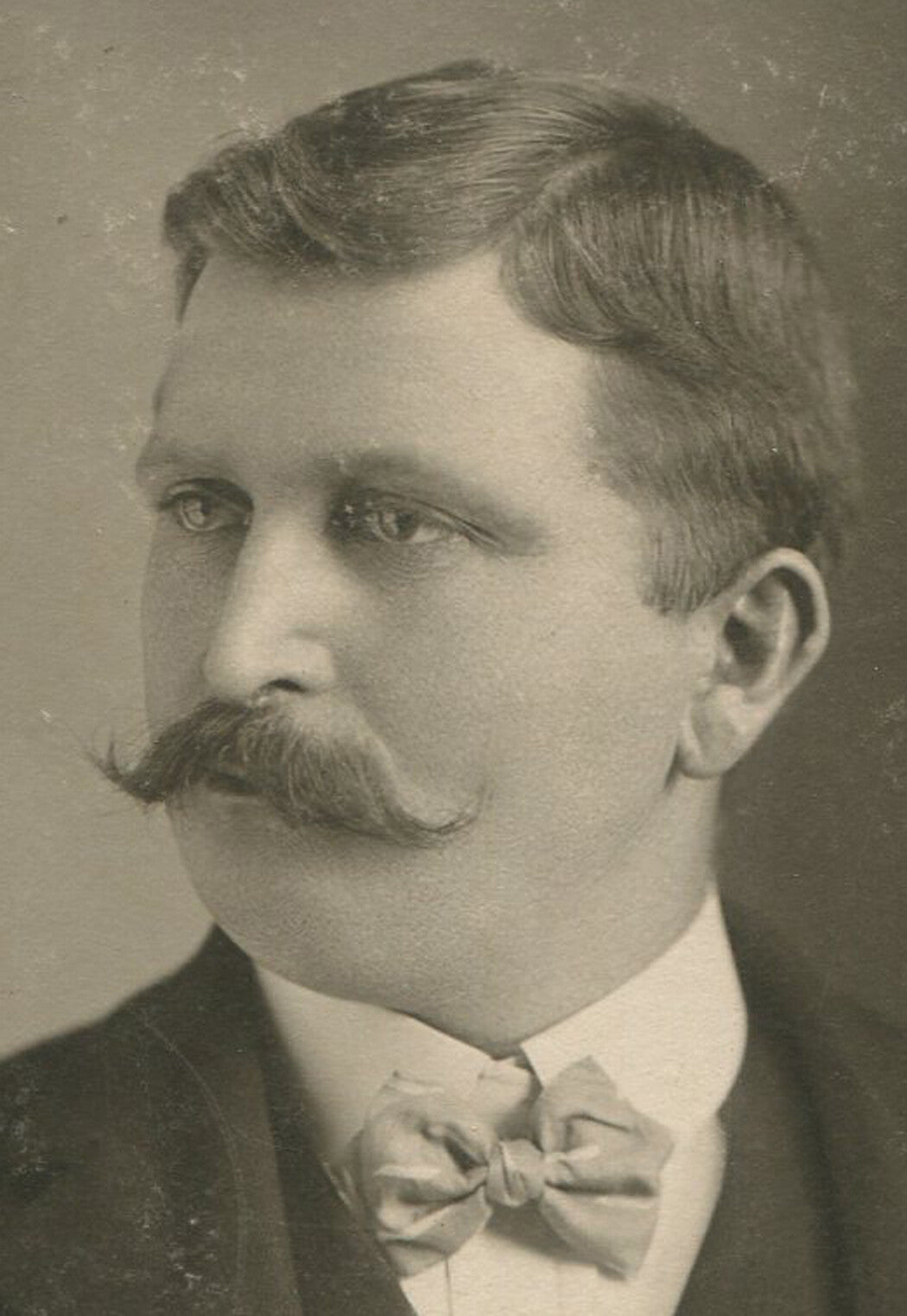 SERIOUS MAN W/SERIOUS MUSTACHE AND UNSERIOUS BOW TIE. CABINET CARD. 1900.