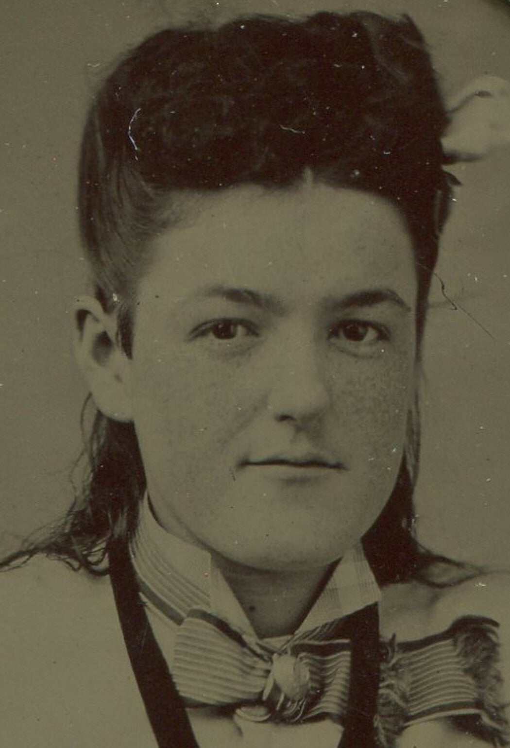 Vintage tintype portrait of a seated woman with crossed arms and high hair on