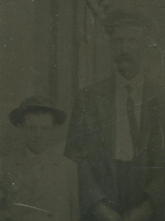 YOUNG BOY W/FATHER, BOTH IN HATS. TINTYPE IN PERIOD PAPER MAT.