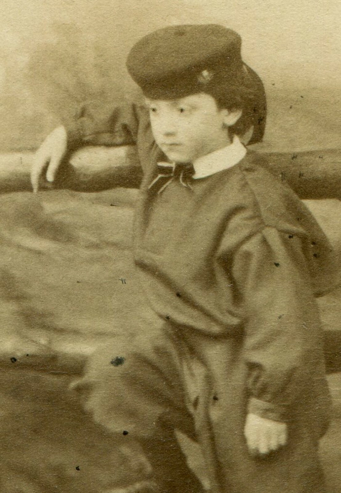 YOUNG BOY IN FANCY OUTFIT/HAT. RUSTIC BACKGROUND. CDV. LONDON, ENGLAND.