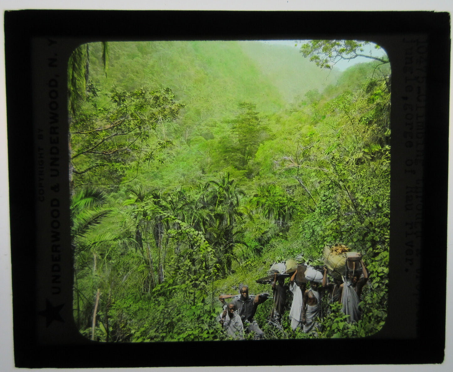 CARRYING GOODS TO MARKET THROUGH JUNGLE. AFRICA.TINTED PHOTO ON GLASS.