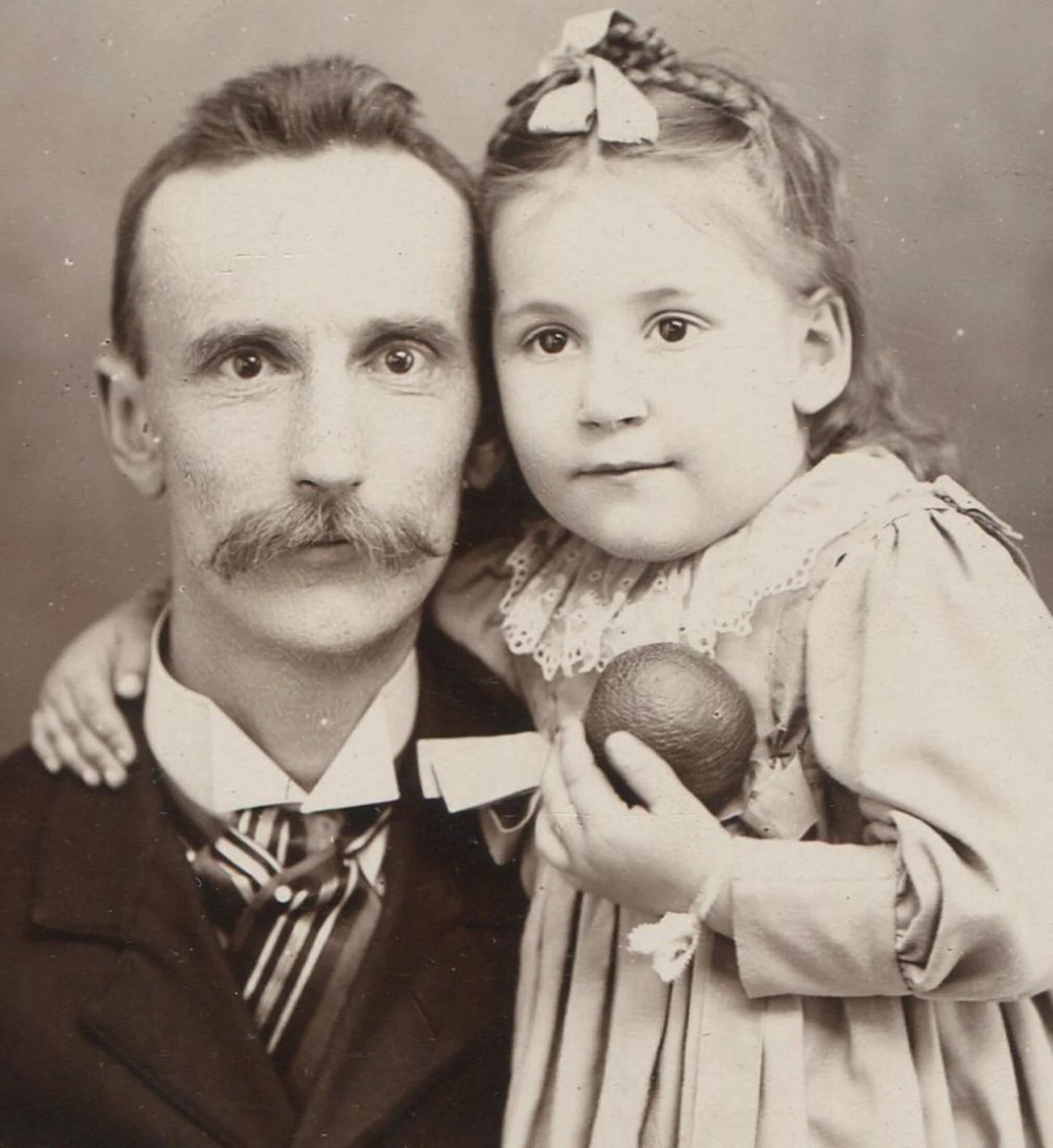 FATHER WITH YOUNG DAUGHTER, HOLDING A TOY. CABINET CARD.