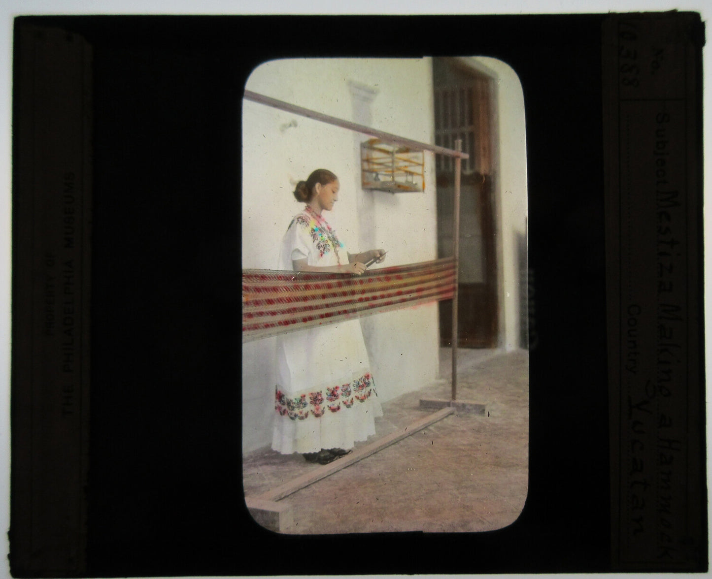 LATIN AMERICAN WOMAN WOMAN AT WEAVING LOOM. HAND COLORED PHOTO ON GLASS.