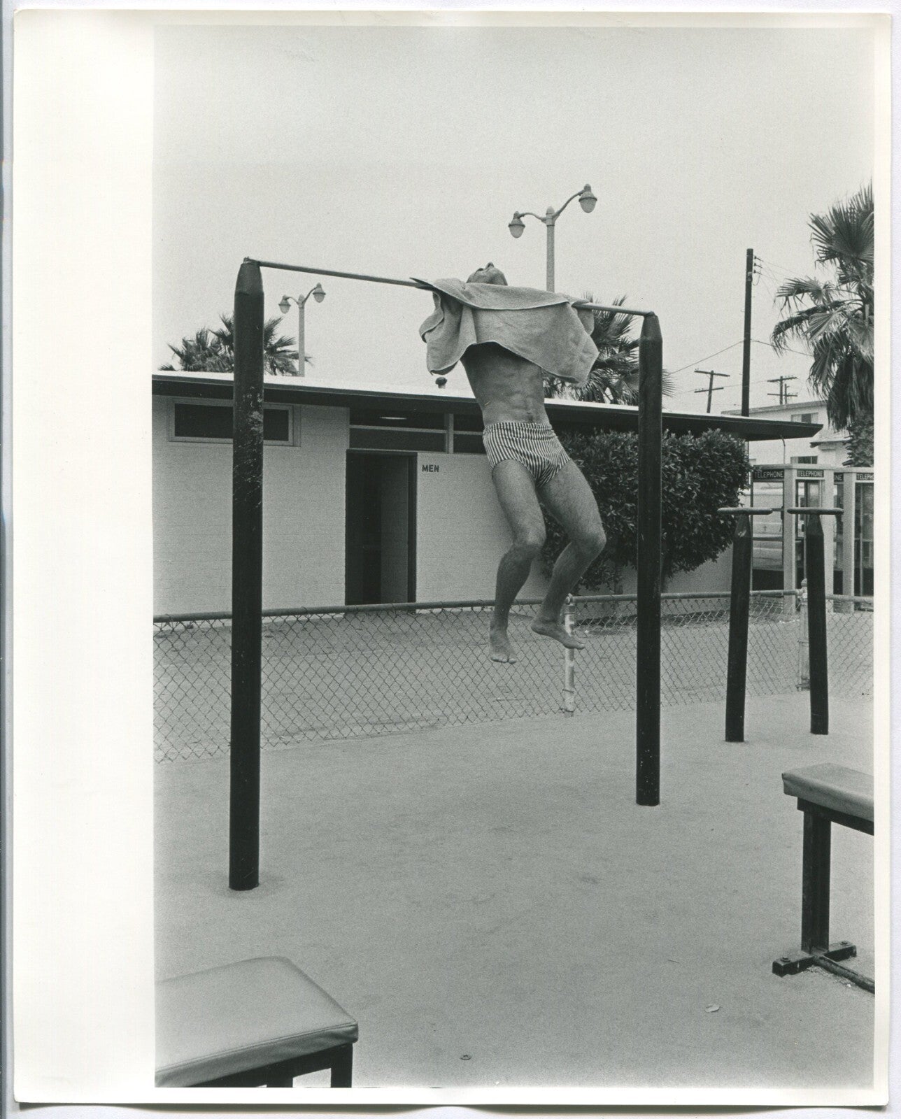 MAN IN SWIM SUIT STRUGGLES TO DO CHIN UP.B&W 8X10.1970s