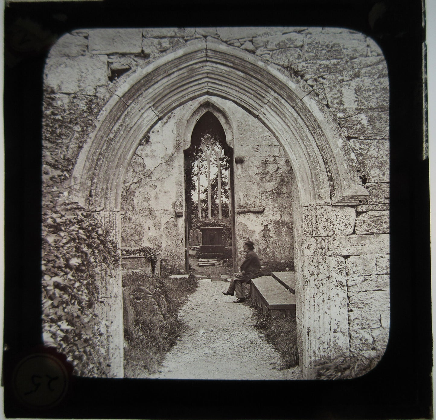 MAN SEATED IN CHURCH RUINS. LANTERN SLIDE.