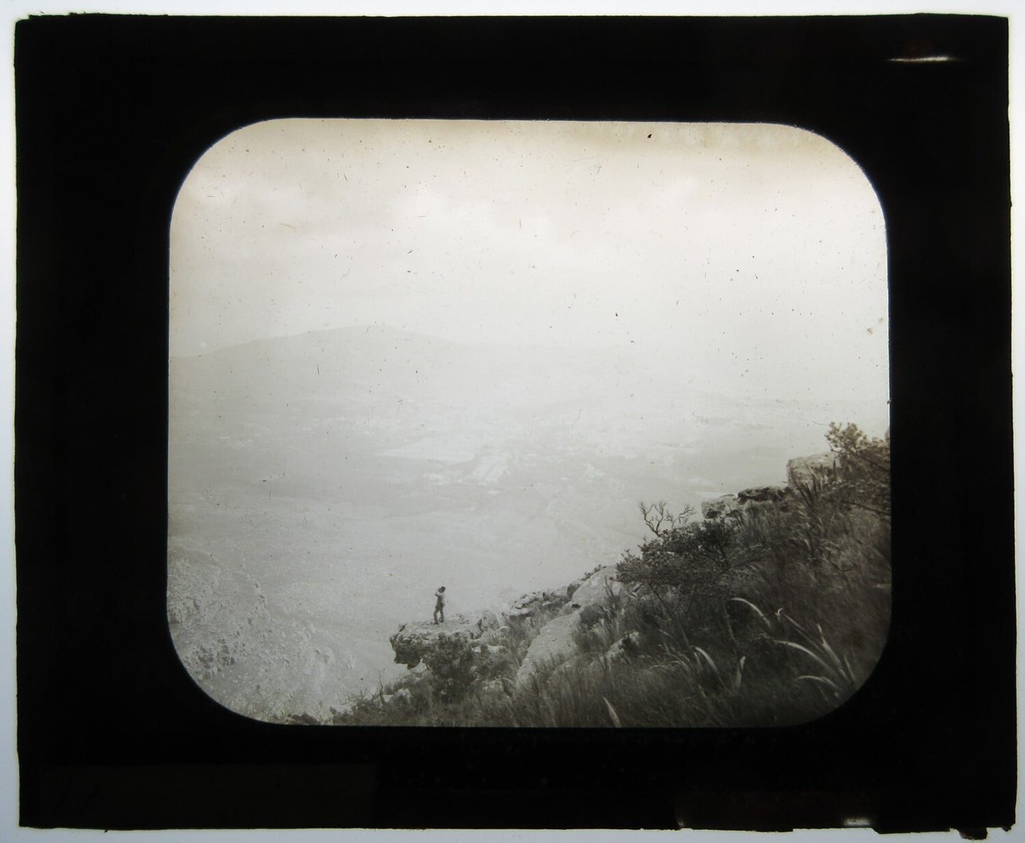 MAN POSED ON BOULDER/CLIFF EDGE. PHOTO ON GLASS.