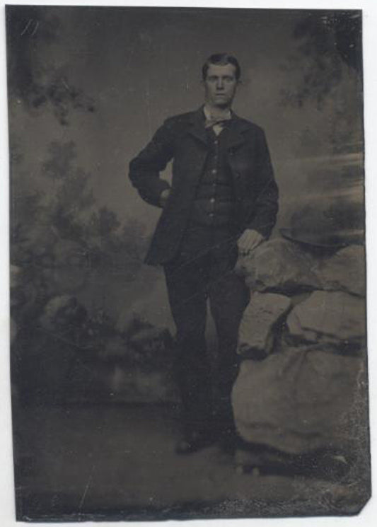UNMOUNTED TINTYPE, TALL MAN POSING WITH ROCK FOR A PORTRAIT. PAINTED BACKDROP.