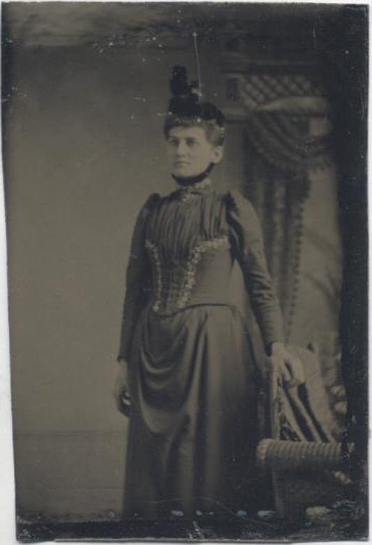 UNMOUNTED TINTYPE, STIFF WOMAN IN A CORSET AND FUNNY HAT. PAINTED BACKDROP.
