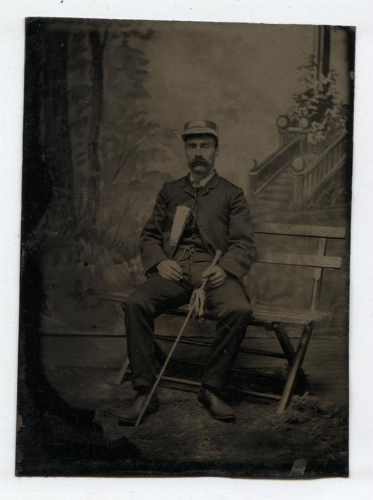 TINTYPE FIREMAN SEATED WEARING FRATERNITY RIBBON HOLDING WALKING STICK.