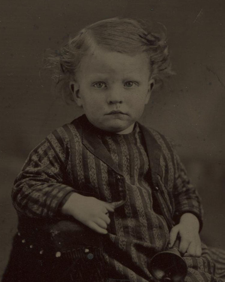 TINTYPE YOUNG CHILD IN STRIPED AND CHECK OUTFIT HOLDING A BELL. TINTED. UNHAPPY.