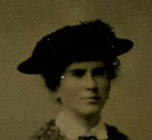WOMAN WEARING HAT, SEATED IN FRONT OF PAINTED BACKGROUND. TINTED TINTYPE.