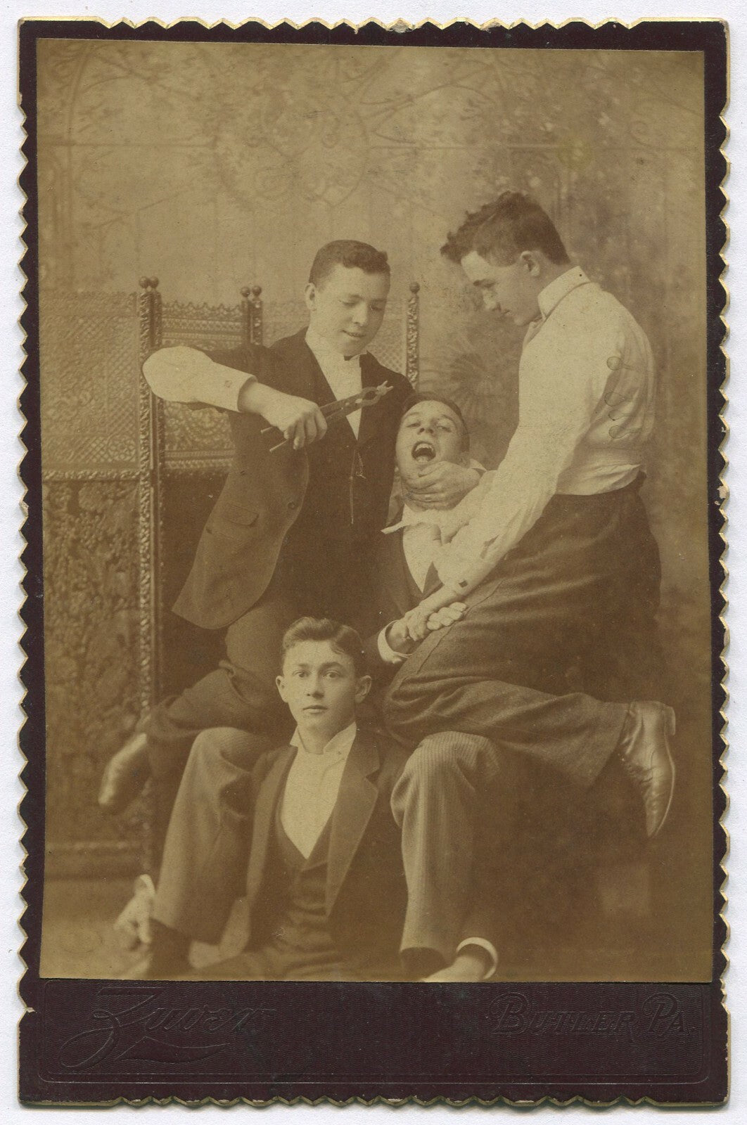 YOUNG MEN ENGAGED IN TOOTH EXTRACTION, COMICAL. CABINET CARD. BUTLER, PA.