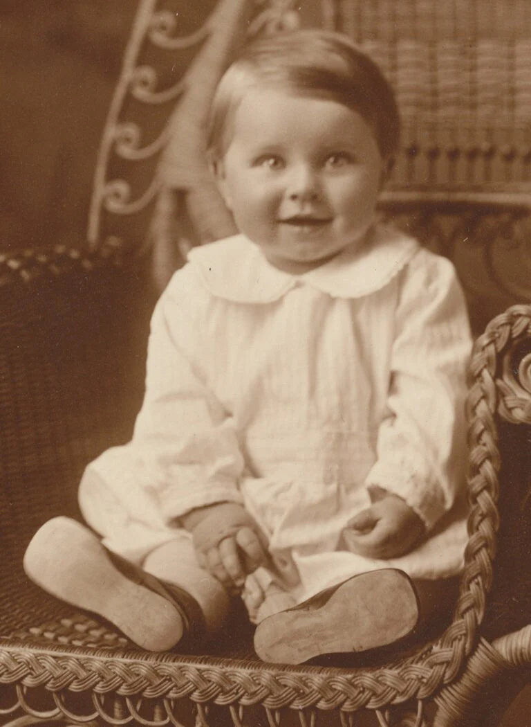 Cute but Scary Baby Smiling on an Ornate Chair. Sepia Toned Print.